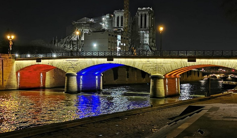 One of bridges near Notre Dame Cathedral illuminated in colors of Armenian and French flags